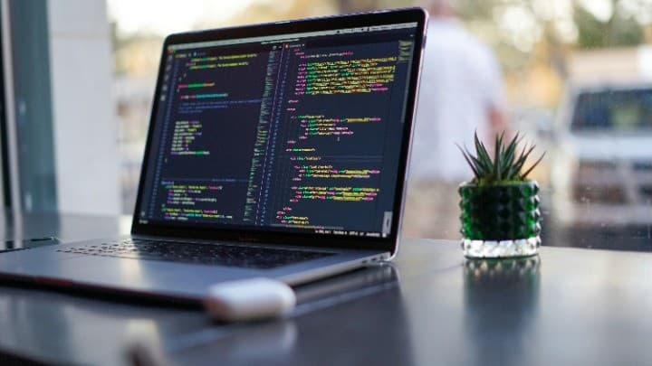 A laptop on a desk showing source code